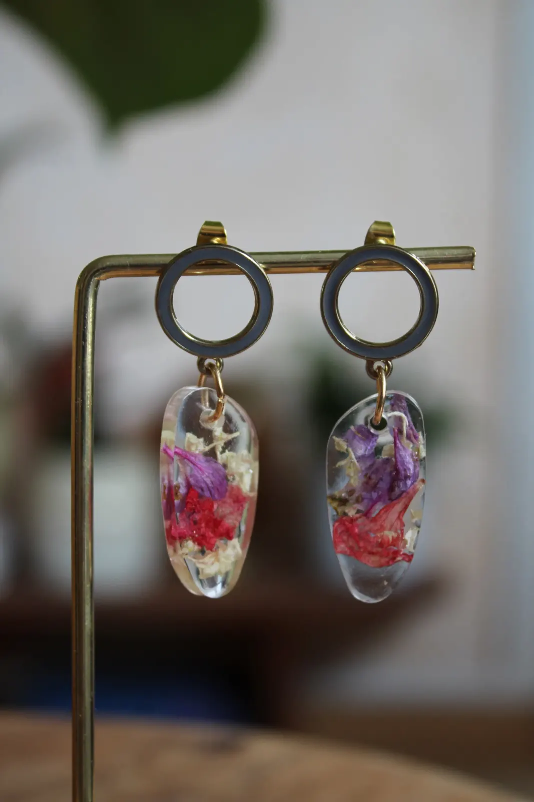 Boucles d'oreilles suspendues à anneaux dorés et gris avec pendentifs en résine et pétales violets et rouges.