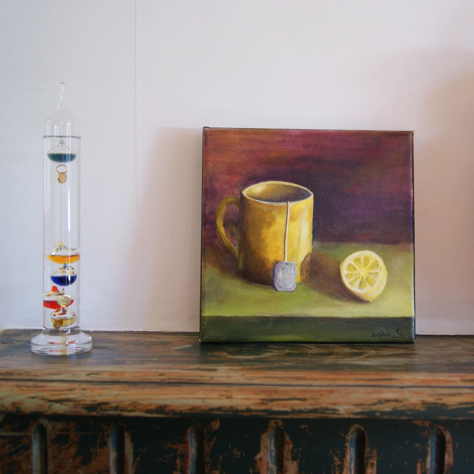 Peinture à l'huile d'une tasse jaune avec sachet d'infusion et demi-citron sur fond pourpre.