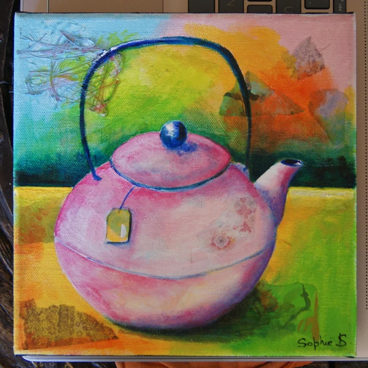 Vue de face du tableau représentant une théière rose sur fond coloré jaune, vert et bleu