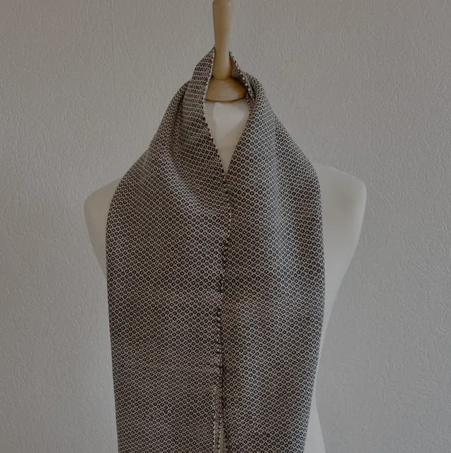 Écharpe à motifs géométriques noir et blanc drapée sur un mannequin de couture.