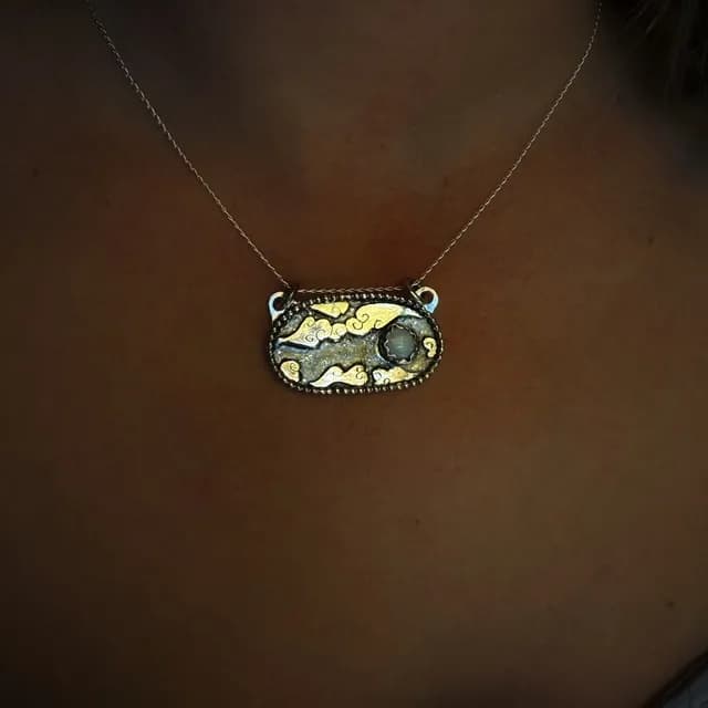 Médaillon ovale gravé de nuages et ciel étoilé orné d'une opale, sur support métallique