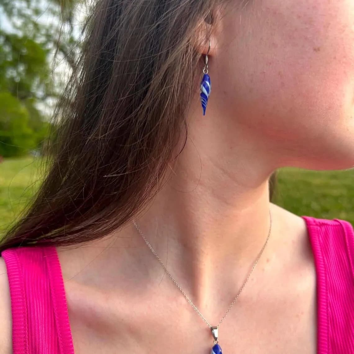 Boucle d'oreille pendante torsadée bleue et blanche portée à l'oreille