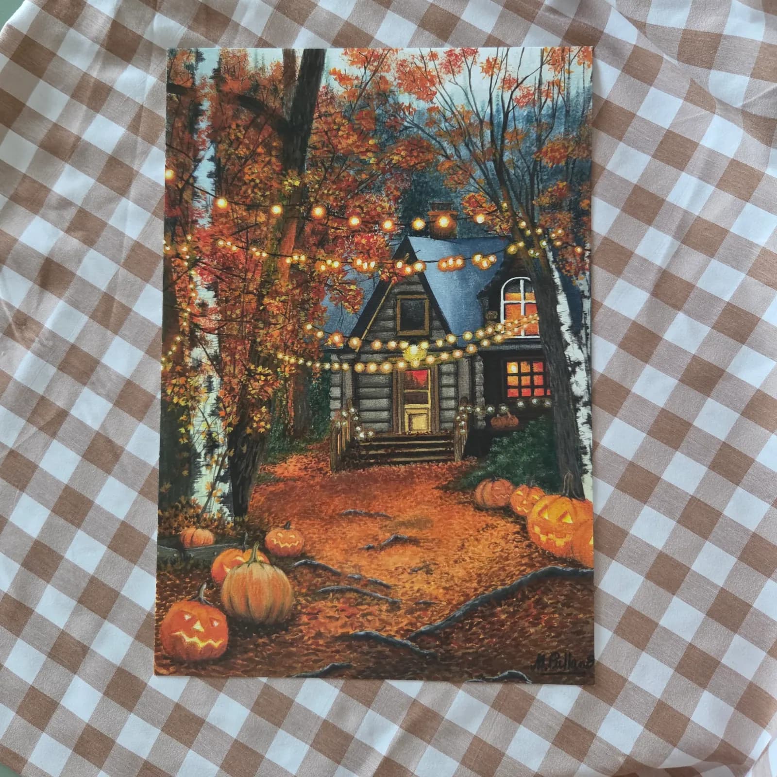 Illustration d'un chalet forestier automnal illuminé avec citrouilles et guirlandes sur fond vichy.
