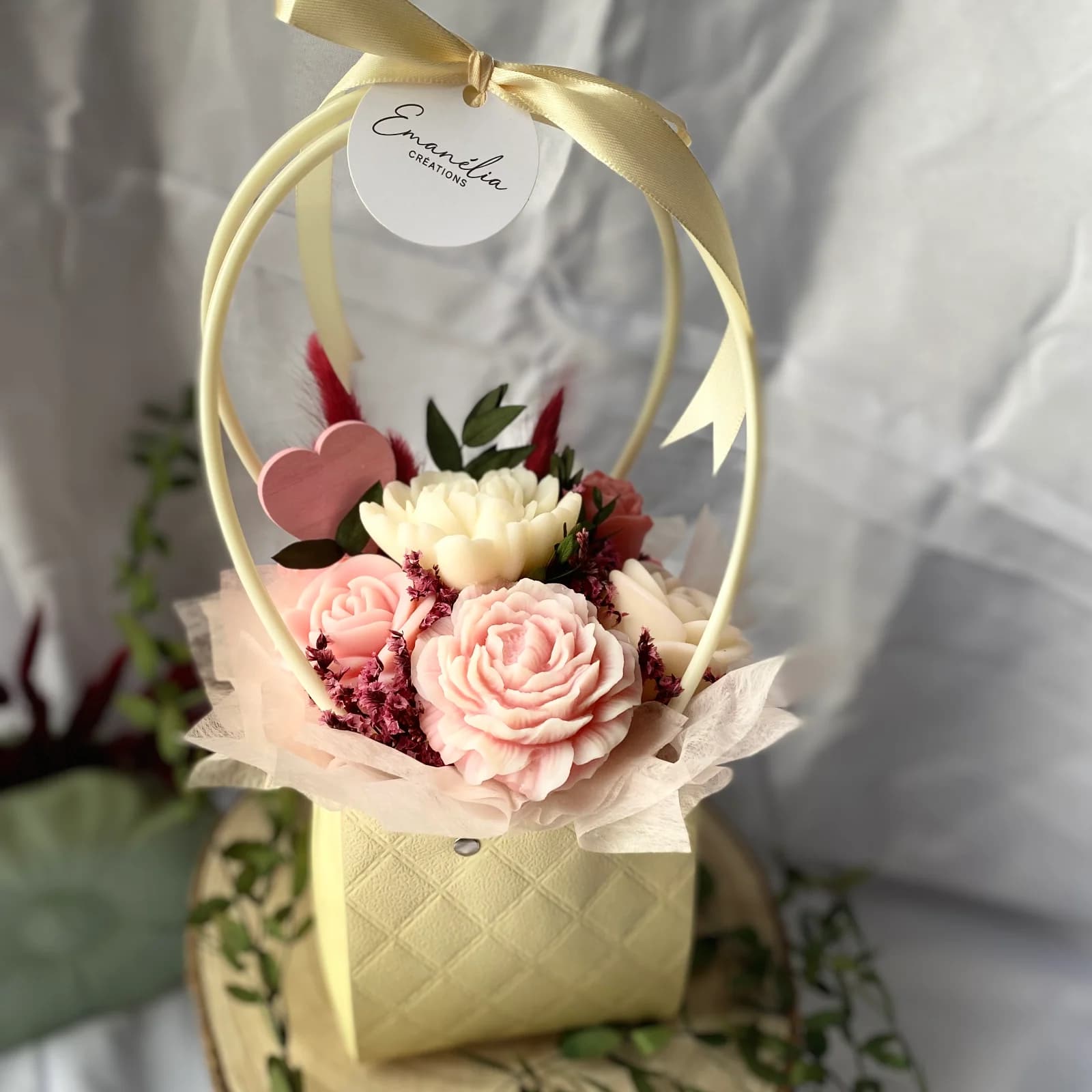 Bouquet de fleurs en cire rose et ivoire dans une boîte panier jaune pastel à ruban